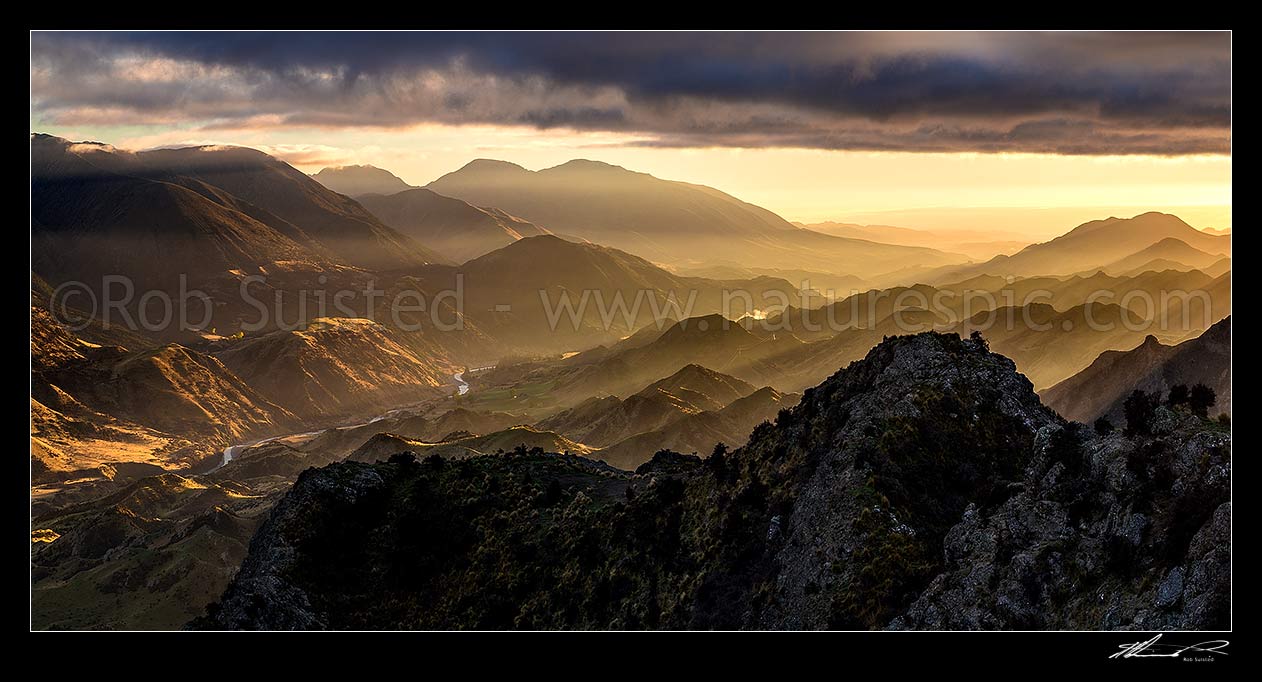 Image of Awatere River Valley dawn, with dramatic sunlight rays over Gladestone Downs and Camden Stations. Hodder River foreground. Panorama, Awatere Valley, Marlborough District, Marlborough Region, New Zealand (NZ) stock photo image