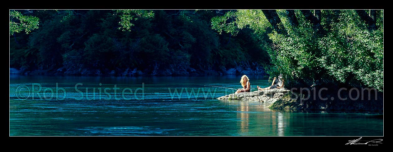 Image of Relaxing sunny summer's day fishing on the Waikato River. Young woman and friend trout fishing under willow trees. Panorama, Taupo, Taupo District, Waikato Region, New Zealand (NZ) stock photo image