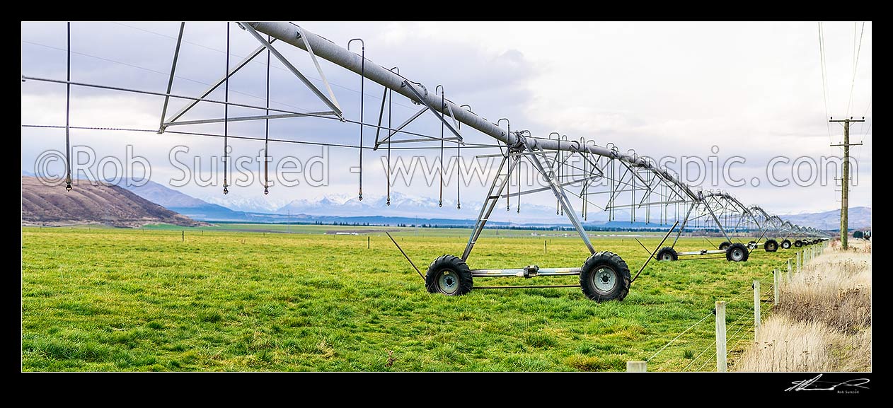 Image of Mackenzie Basin irrigation and pasture improvement for dairy farming. Pivot irrigator with southern alps behind (Burnett Mountains and Gamack Range etc). Irrigator in focus. Panorama, Twizel, MacKenzie District, Canterbury Region, New Zealand (NZ) stock photo image