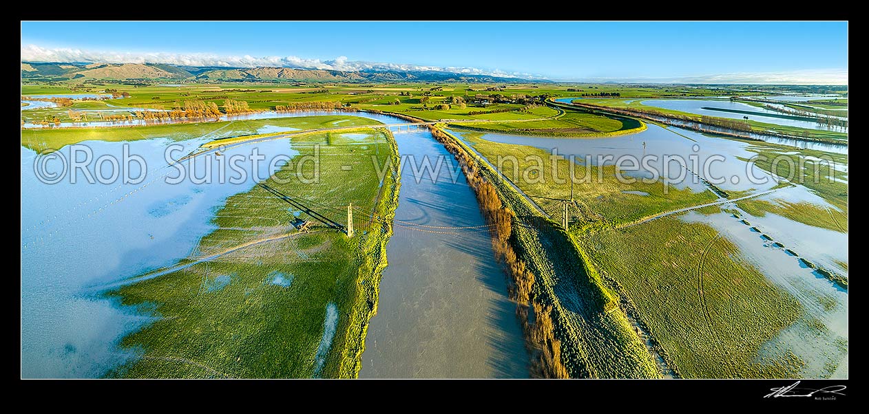 Image of Farmland flooded by the Manawatu River.  State Highway 56 (SH56, left) underwater, and dairy farmland inundated by flood waters. Aerial panorama looking south over historic Opiki toll bridge towards Tararua Ranges, Opiki, Horowhenua District, Manawatu-Wanganui Region, New Zealand (NZ) stock photo image