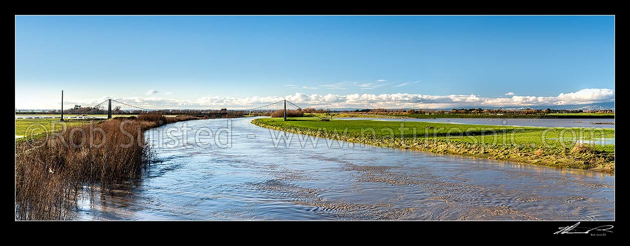 Image of Manawatu River under flood flow levels, passing under the historic Opiki toll bridge (1918). Tane flax mill chimney at left. Panorama, Opiki, Horowhenua District, Manawatu-Wanganui Region, New Zealand (NZ) stock photo image