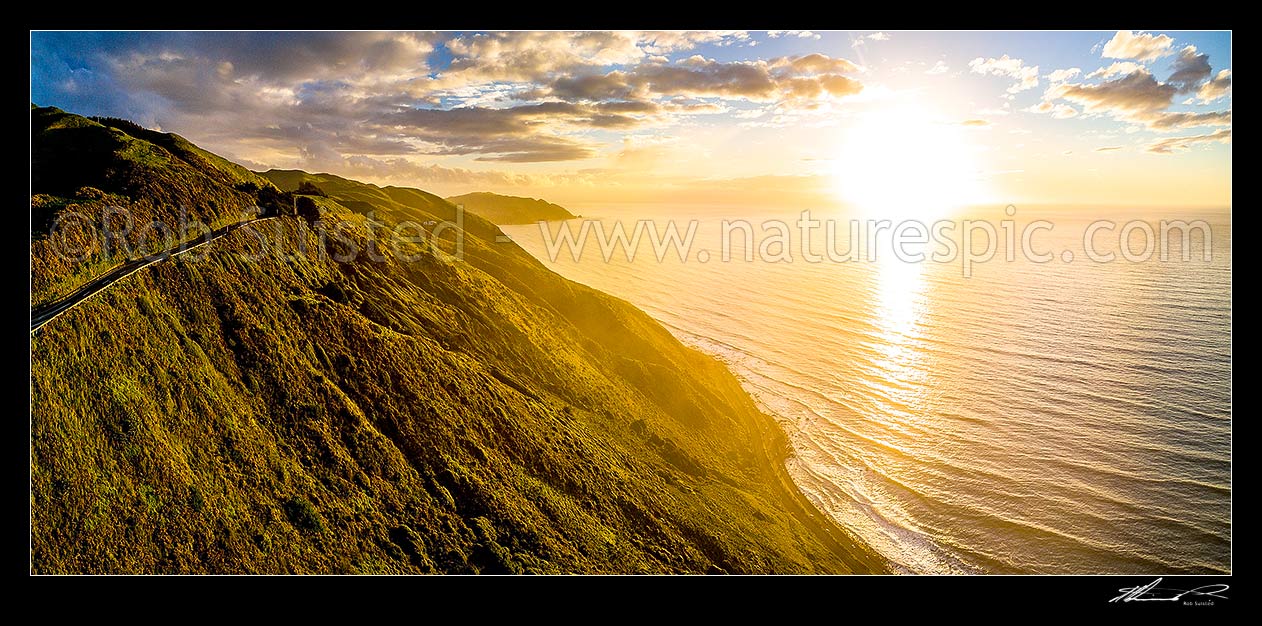 Image of Paekakariki to Pukerua Bay SH1 road passing below the Paekakariki Hill Road. Sunset over Pukerua Bay coastline. Wairaka Point distant. Aerial panorama, Paekakariki, Kapiti Coast District, Wellington Region, New Zealand (NZ) stock photo image