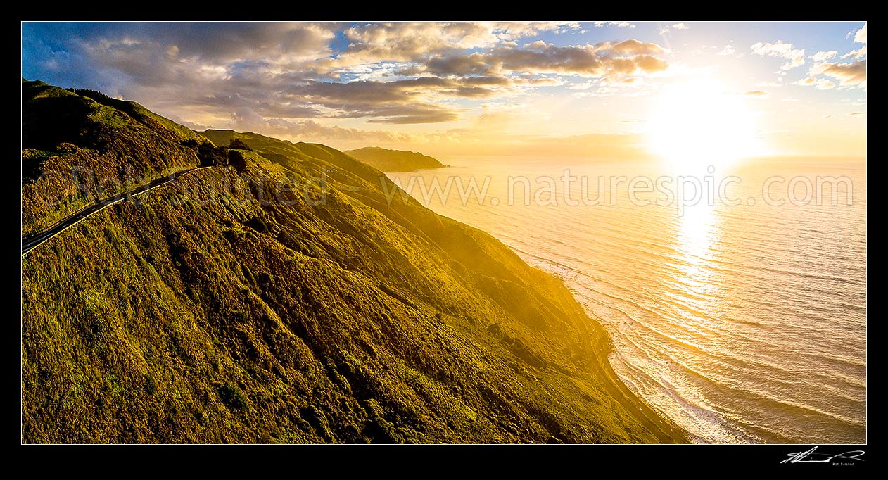 Image of Paekakariki to Pukerua Bay SH1 road passing below the Paekakariki Hill Road. Sunset over Pukerua Bay coastline. Wairaka Point distant. Aerial panorama, Paekakariki, Kapiti Coast District, Wellington Region, New Zealand (NZ) stock photo image