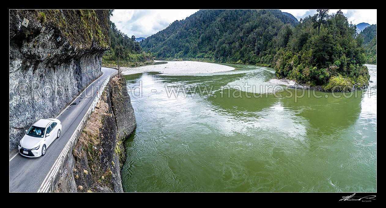 Image of Hawks Crag under cut in the Buller Gorge, beside the Buller River and Dee Point (right). State Highway 6 (SH6). Aerial panorama of car passing underneath this narrow section in Lower Buller Gorge, Westport, Buller District, West Coast Region, New Zealand (NZ) stock photo image