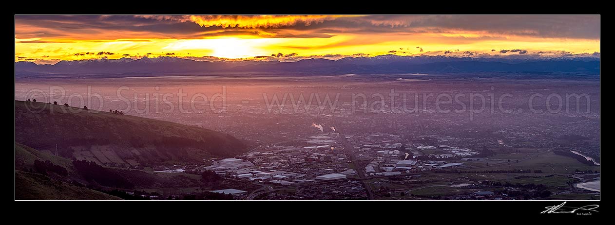 Image of Christchurch City and Canterbury plains on a calm winter evening with fog settling and snow on the Southern Alps beyond. Sunset panorama, Port Hills, Christchurch, Christchurch City District, Canterbury Region, New Zealand (NZ) stock photo image