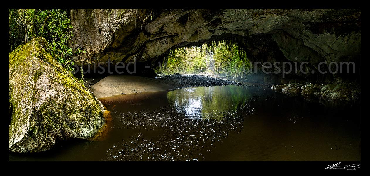 Image of Oparara Arch. The Oparara River entering the little Oparara arch (Moria Gate). Clean, dark, tanin stained water moving slowly under the limestone arch. Panorama, Karamea,Kahurangi National Park, Buller District, West Coast Region, New Zealand (NZ) stock photo image