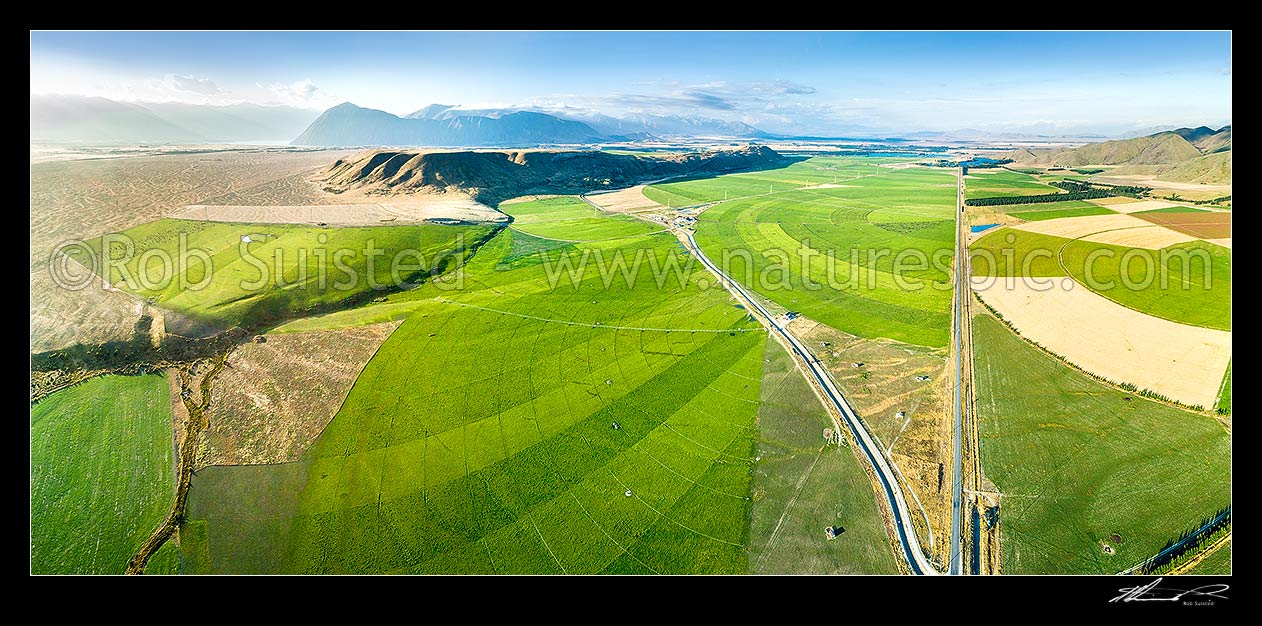 Image of Mackenzie Basin under irrigation. Large pivot irrigators turn the dry alpine glacial outwash plains (left) into lush fertile dairy farms, and change an iconic landscape. Aerial panorama, Twizel, MacKenzie District, Canterbury Region, New Zealand (NZ) stock photo image