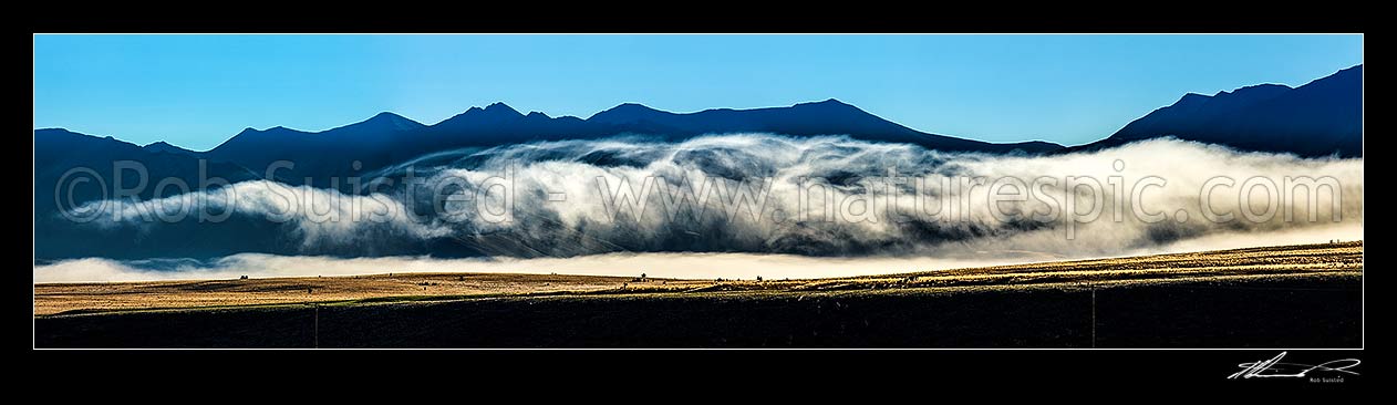 Image of MacKenzie Basin barren high country farmland traversed by powerlines and powerpoles on a moody dawn. Panorama. Abstract, Tekapo, MacKenzie District, Canterbury Region, New Zealand (NZ) stock photo image