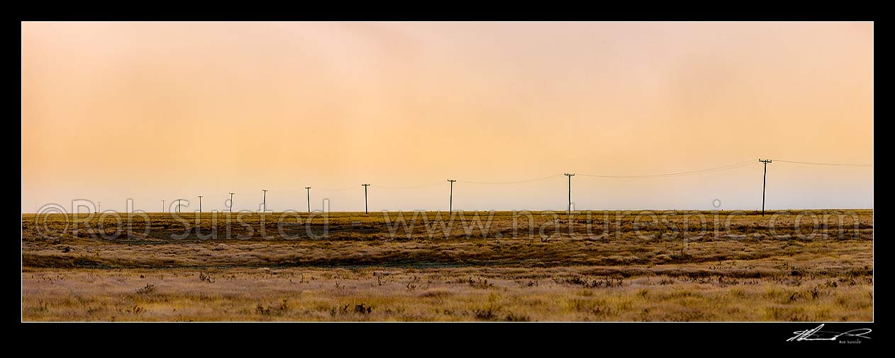 Image of MacKenzie Basin barren high country farmland traversed by powerlines and powerpoles on a moody dawn. Panorama. Abstract, Tekapo, MacKenzie District, Canterbury Region, New Zealand (NZ) stock photo image