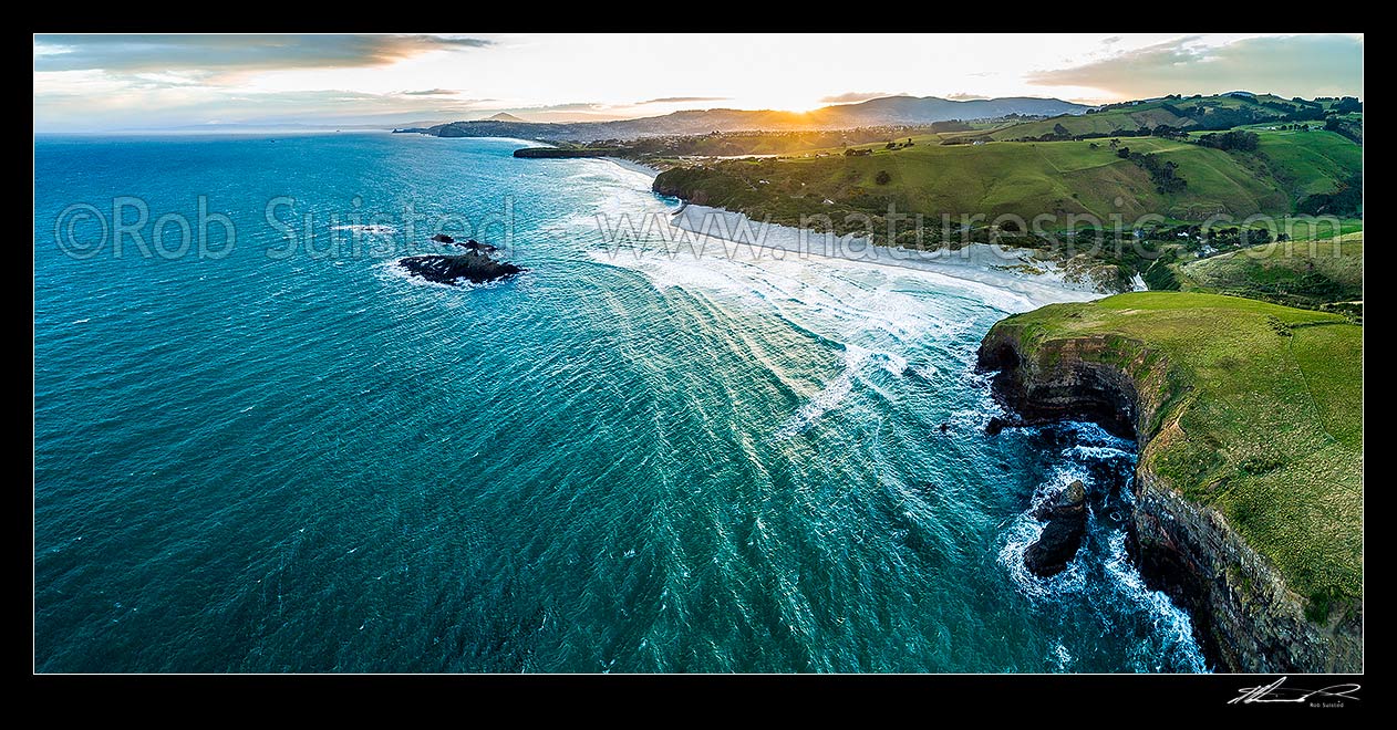 Image of Dunedin South Coast, looking along Smaills Beach to Tomahawk Beach, Lawyers Head and St Kilda behind. Bird Island at left. Aerial panorama at sunset, from near Maori Head, Otago Peninsula, Dunedin City District, Otago Region, New Zealand (NZ) stock photo image