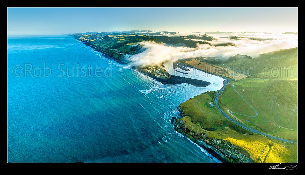 Image of Mokau township at the mouth of the Mokau River, as morning mist hangs in valleys. Aerial panorama looking north from Pakikau towards Awakino River. North Taranaki, Mokau, Waitomo District, Waikato Region, New Zealand (NZ) stock photo image