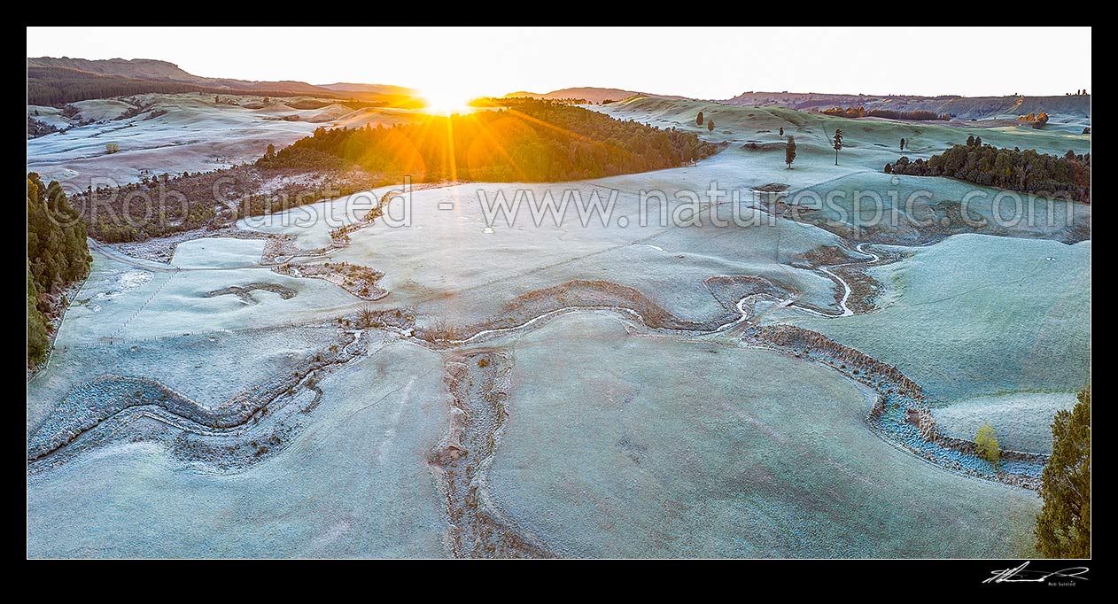 Image of Balls Clearing Scenic Reserve and Clifton Conservation Area at dawn with heavy frost, as sun rises over hill. Headwaters of Mangatutu Stream. Aerial panorama, Puketitiri, Hastings District, Hawke's Bay Region, New Zealand (NZ) stock photo image