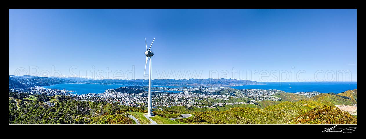 Image of Wellington's Brooklyn wind turbine above Wellington Wellington City and Harbour left, and Cape Turakirae, South coast and Cook Strait right. Aerial panorama view, Wellington, Wellington City District, Wellington Region, New Zealand (NZ) stock photo image