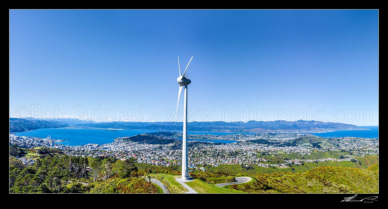 Image of Wellington's Brooklyn wind turbine above Wellington Wellington City and Harbour left, and Cape Turakirae, South coast and Cook Strait right. Aerial panorama view, Wellington, Wellington City District, Wellington Region, New Zealand (NZ) stock photo image