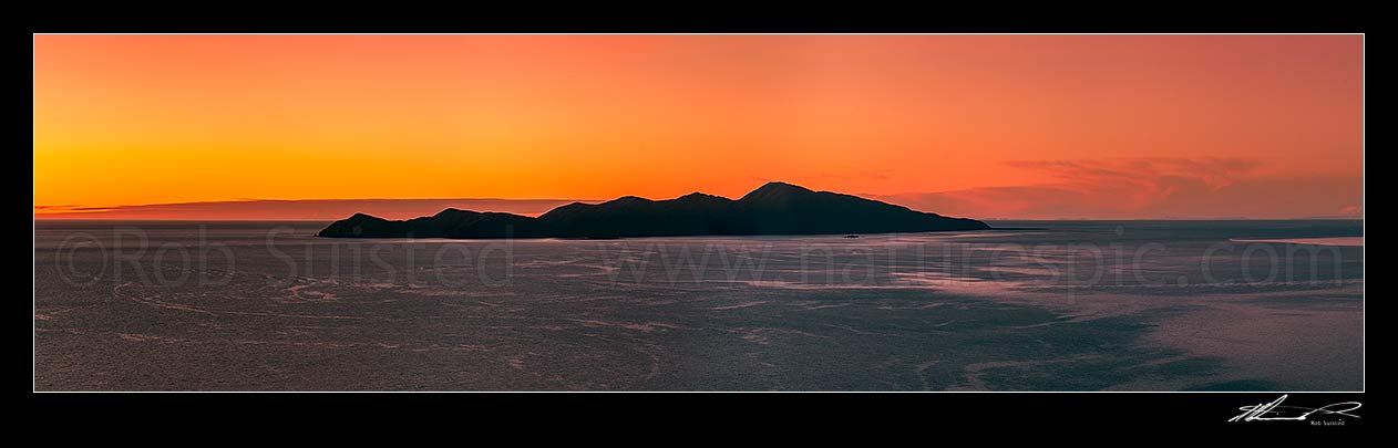 Image of Kapiti Island fiery sunset panorama. Mt Taranaki visible left of Kapiti, and Mt Ruapehu visible far right, Paraparaumu, Kapiti Coast District, Wellington Region, New Zealand (NZ) stock photo image