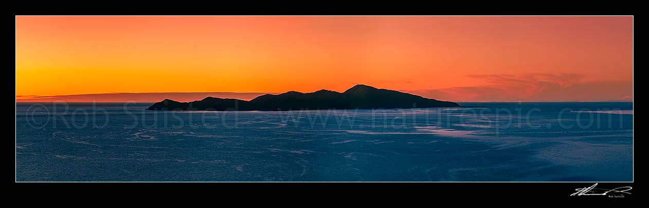 Image of Kapiti Island fiery sunset panorama. Mt Taranaki visible left of Kapiti, and Mt Ruapehu visible far right, Paraparaumu, Kapiti Coast District, Wellington Region, New Zealand (NZ) stock photo image