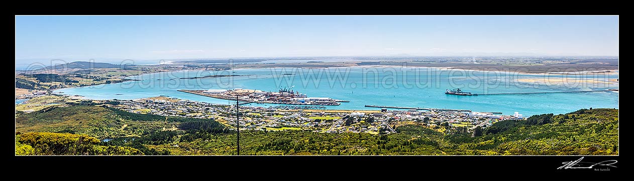 Image of Bluff Harbour with Bluff Port and township centre, and Tiwai wharf at right. View from Bluff Hill. Oreti Beach and New River Estuary distant left. Panorama, Bluff, Invercargill District, Southland Region, New Zealand (NZ) stock photo image