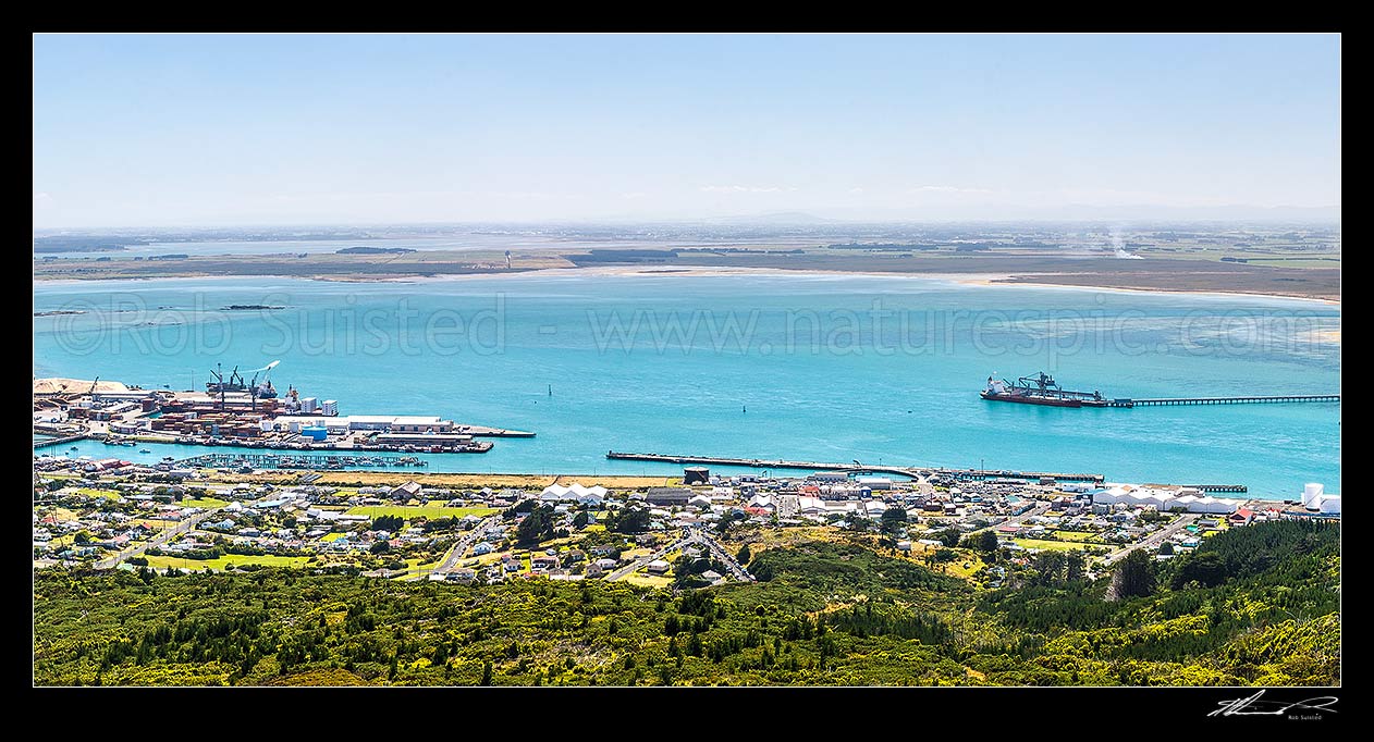 Image of Bluff Harbour with Bluff Port and township, viewed from Bluff Hill with Tiwai Wharf right. New River Estuary distant left, Invercargill City distant centre. Panorama, Bluff, Invercargill District, Southland Region, New Zealand (NZ) stock photo image