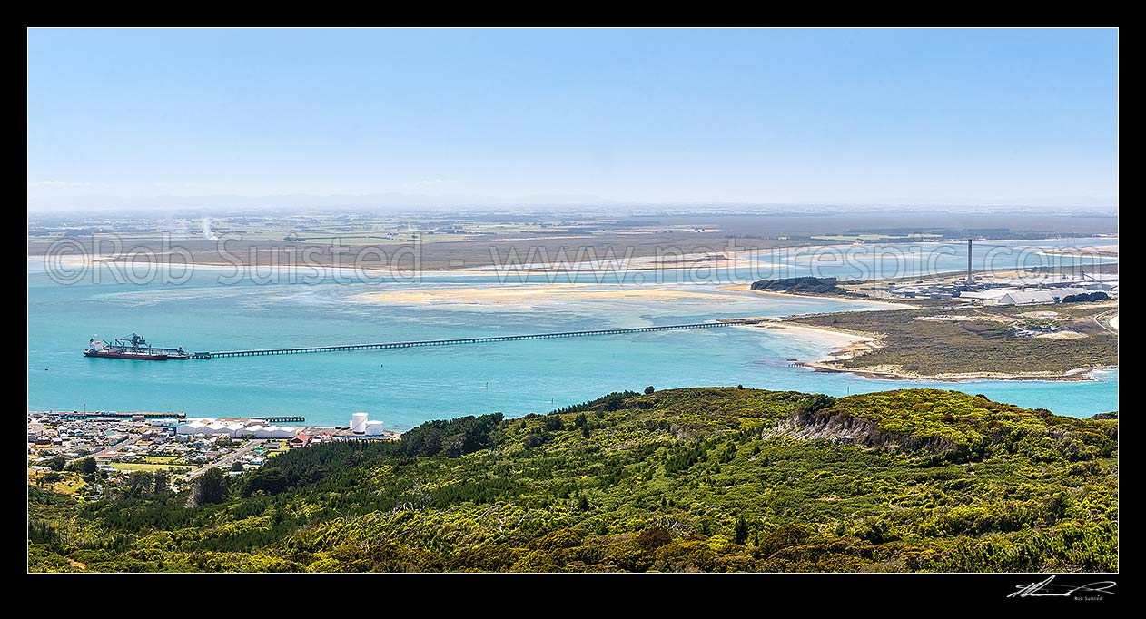 Image of Tiwai Point aluminium smelter, with bulk carrier ship Africa Bulker unloading Bauxite to Tiwai Point aluminium smelter via Tiwai Wharf. Awarua Bay behind. Panorama, Bluff, Invercargill District, Southland Region, New Zealand (NZ) stock photo image