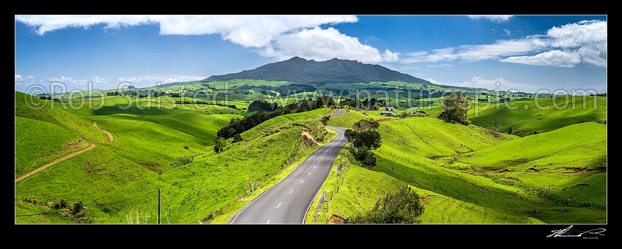 Image of Mount Karioi (756m) high above coastal Waikato farmland. View over lush rural land, road, and pasture, Raglan, Waikato District, Waikato Region, New Zealand (NZ) stock photo image