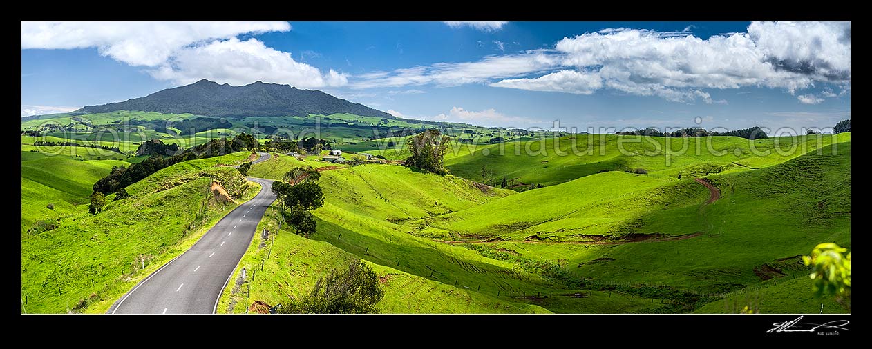 Image of Mount Karioi (756m) high above coastal Waikato farmland. View over lush rural land, road, and pasture, Raglan, Waikato District, Waikato Region, New Zealand (NZ) stock photo image