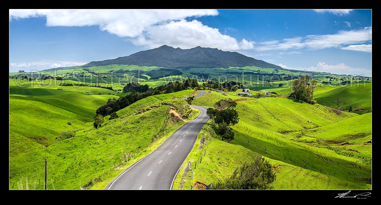 Image of Mount Karioi (756m) high above coastal Waikato farmland. View over lush rural land, road, and pasture, Raglan, Waikato District, Waikato Region, New Zealand (NZ) stock photo image