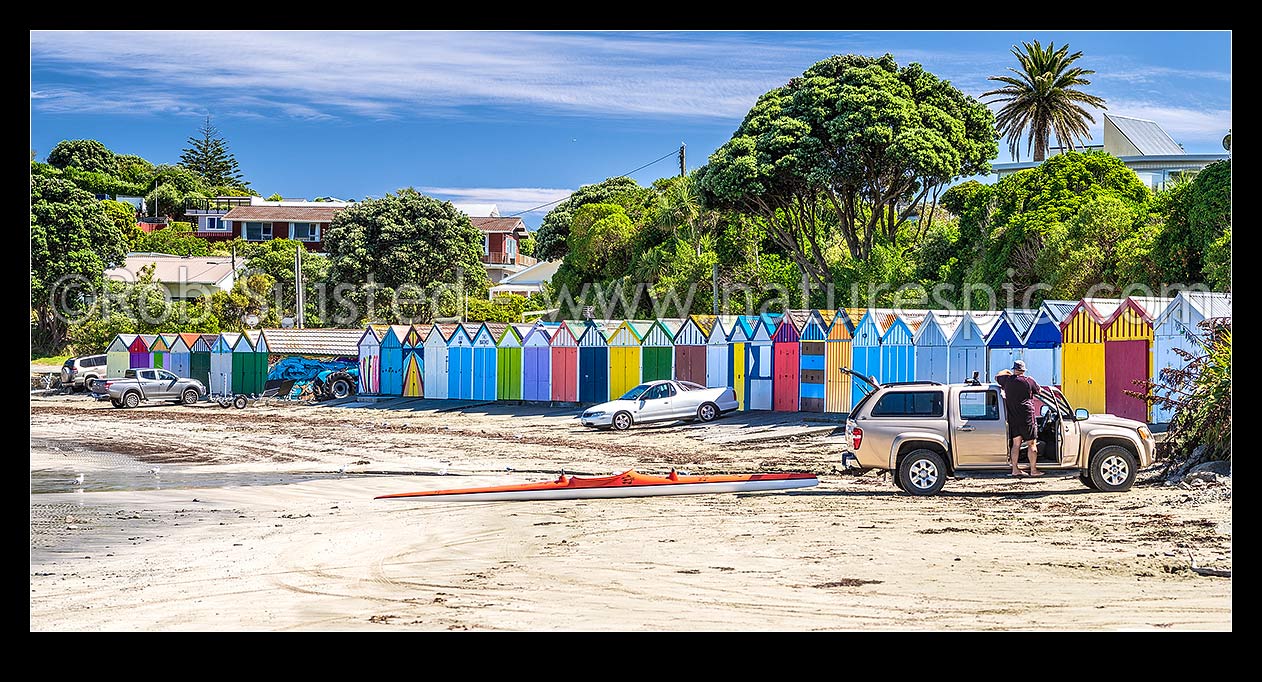 Image of Titahi Bay boatsheds, iconic brightly painted sheds on Titahi Bay beach front, north end, with waka ama paddler loading car. Panorama, Titahi Bay, Porirua City District, Wellington Region, New Zealand (NZ) stock photo image