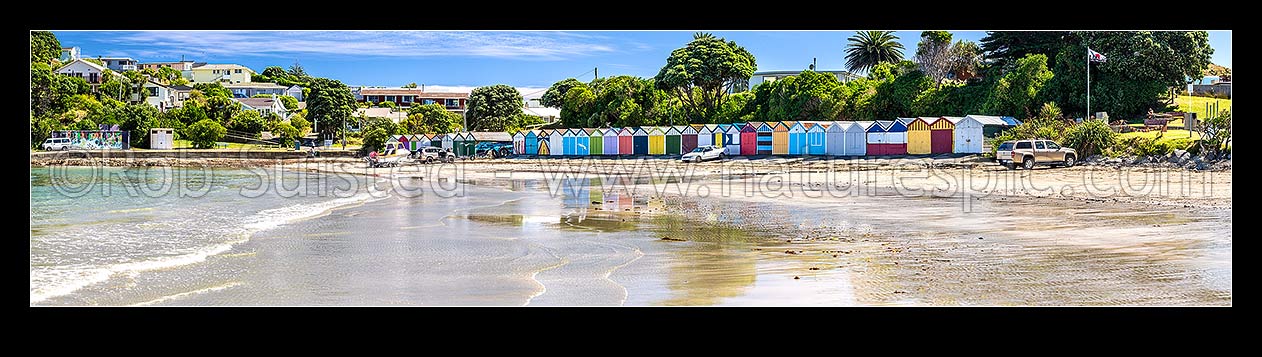 Image of Titahi Bay boatsheds, iconic brightly painted sheds on Titahi Bay beach front, north end, with boat about to be launched. Panorama, Titahi Bay, Porirua City District, Wellington Region, New Zealand (NZ) stock photo image