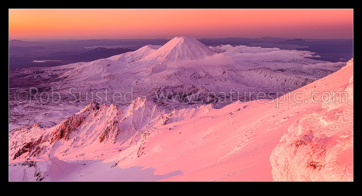 Image of Mount Ngauruhoe (2287m) from Mt Ruapehu at sunset. Pinnacle Ridge in foreground, Tama Lakes mid ground and Mt Tongariro (1967m) and Lake Taupo behind. Heavy winter snow. Panorama, Tongariro National Park, Ruapehu District, Manawatu-Wanganui Region, New Zealand (NZ) stock photo image