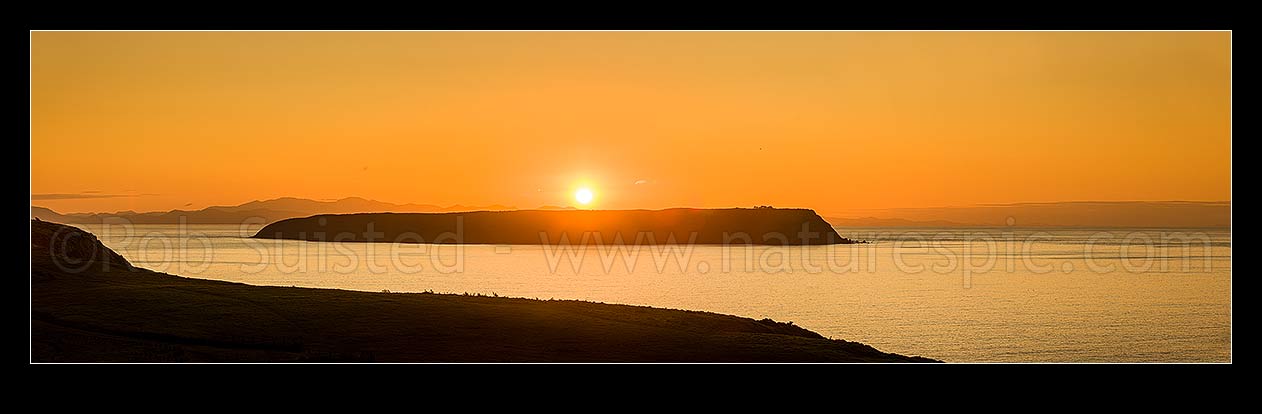 Image of Mana Island sunset on a calm evening. Seem from Whitireia Park. Cook Strait and South Island behind. Panorama, Titahi Bay, Porirua City District, Wellington Region, New Zealand (NZ) stock photo image