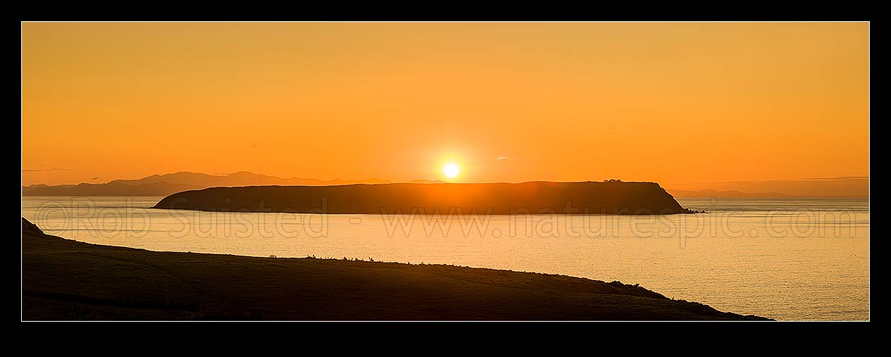 Image of Mana Island sunset on a calm evening. Seem from Whitireia Park. Cook Strait and South Island behind. Panorama, Titahi Bay, Porirua City District, Wellington Region, New Zealand (NZ) stock photo image