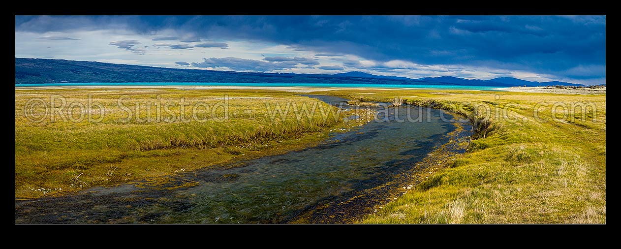 Image of Lake Pukaki's turquoise blue waters against a heavy moody sky. Lake Pukaki lake shore and edge in the Tasman Valley where a spring fed creek passes. Panorama, Lake Pukaki, MacKenzie District, Canterbury Region, New Zealand (NZ) stock photo image