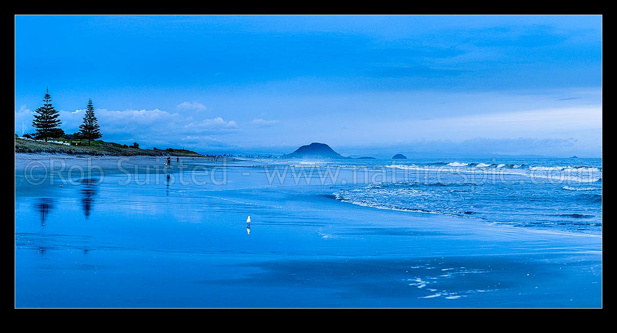 Image of Papamoa Beach and surf, summer pre-dawn as people exercise early morning. Mount Maunganui Mauao behind. Panorama, Papamoa Beach, Tauranga District, Bay of Plenty Region, New Zealand (NZ) stock photo image