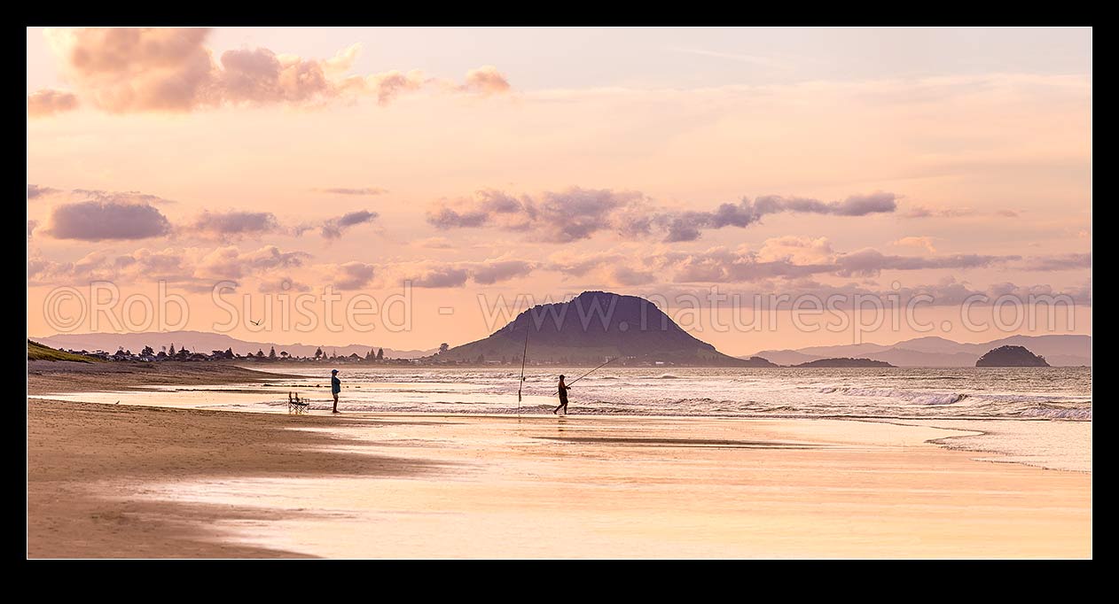 Image of Papamoa Beach evening twilight looking west towards Mt Maunganui Mauao (231m). People surfcasting fishing on golden beach. Panorama, Papamoa Beach, Tauranga District, Bay of Plenty Region, New Zealand (NZ) stock photo image