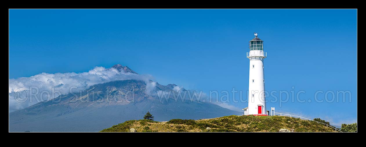 Image of Cape Egmont and lighthouse, with a cloud cloaked Mount Taranaki (2518m) behind. Panorama, Cape Egmont, South Taranaki District, Taranaki Region, New Zealand (NZ) stock photo image