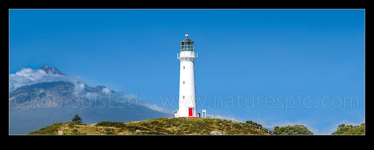 Image of Cape Egmont and lighthouse, with a cloud cloaked Mount Taranaki (2518m) behind. Panorama, Cape Egmont, South Taranaki District, Taranaki Region, New Zealand (NZ) stock photo image