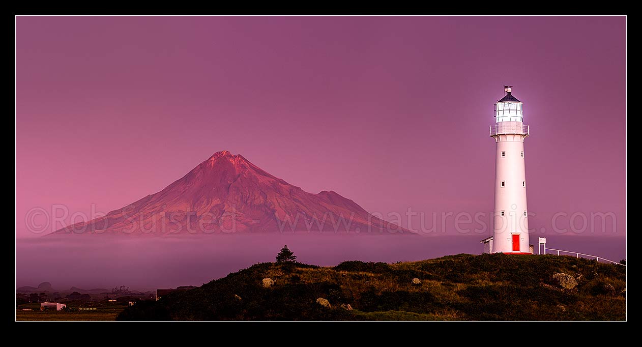 Image of Cape Egmont lighthouse with Mount Taranaki (2518m) and Egmont National Park behind, in the post dusk twilight. Panorama, Cape Egmont, South Taranaki District, Taranaki Region, New Zealand (NZ) stock photo image