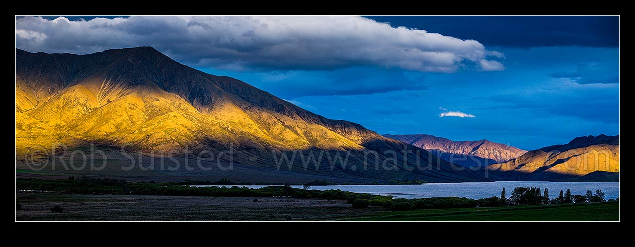 Image of Lake Benmore and surrounding high country hills in evening light. Moody panorama, Otematata, MacKenzie District, Canterbury Region, New Zealand (NZ) stock photo image