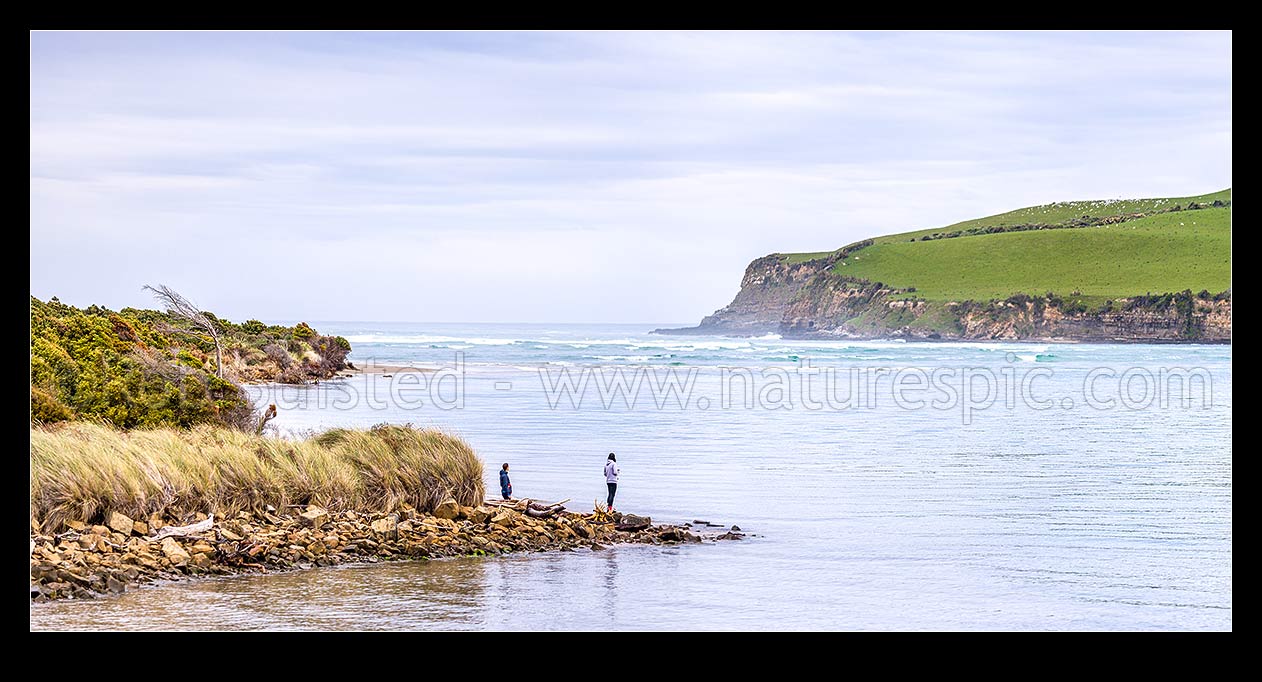 Image of Catlins River mouth at Surat Bay New Haven, with Catlins Head beyond, at high tide. Visitors enjoying the sight. Panorama, Catlins, Clutha District, Otago Region, New Zealand (NZ) stock photo image