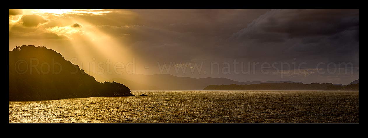 Image of Sunlit rays over Paterson Inlet Whaka a Te Wera. Evening crepusular rays lighting Ulva Island at left. Rakiura panorama, Paterson Inlet, Stewart Island District, Southland Region, New Zealand (NZ) stock photo image