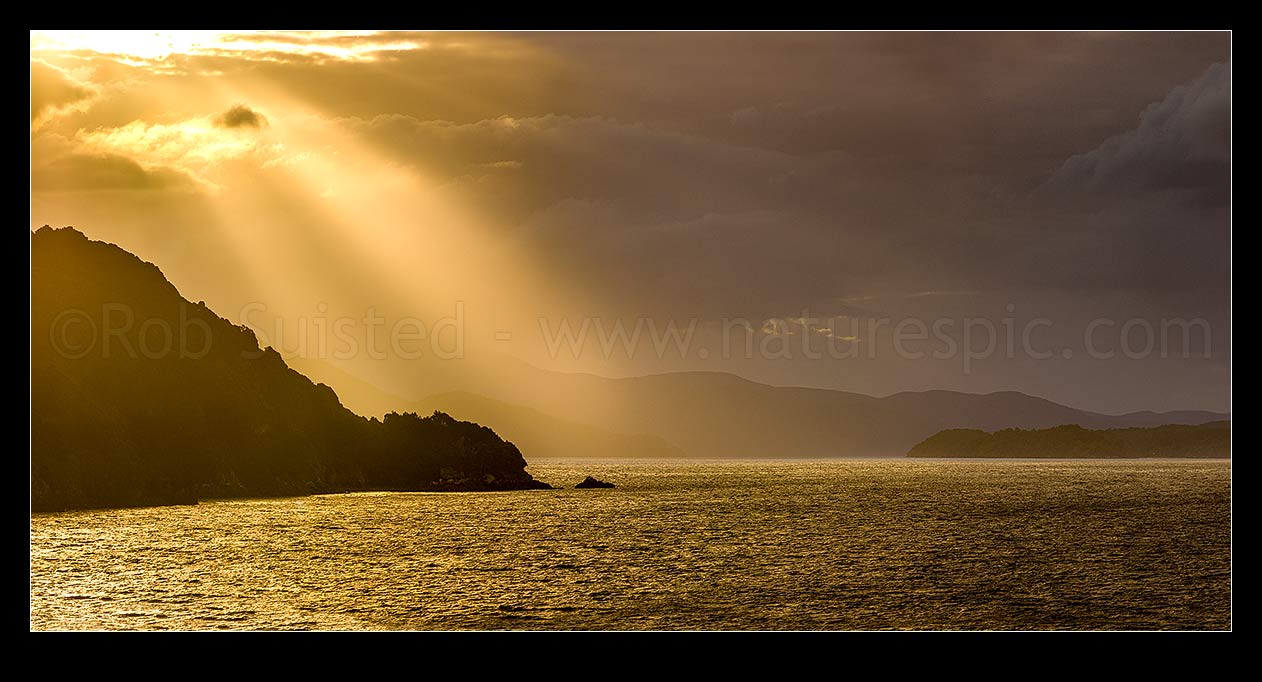 Image of Sunlit rays over Paterson Inlet Whaka a Te Wera. Evening crepusular rays lighting Ulva Island at left. Rakiura panorama, Paterson Inlet, Stewart Island District, Southland Region, New Zealand (NZ) stock photo image