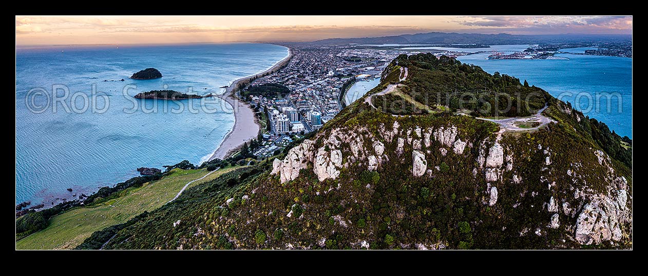 Image of Mt Maunganui summit Mauao at the Tauranga Harbour Entrance. 231m high lava dome. Mt Maunganui Beach left, Tauranga Harbour right. Aerial panorama at dusk, Mount Maunganui, Tauranga District, Bay of Plenty Region, New Zealand (NZ) stock photo image