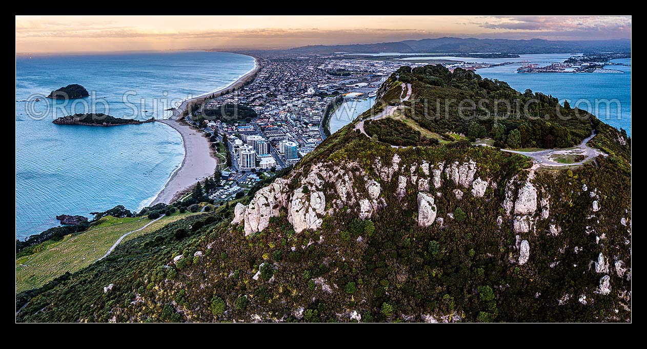 Image of Mt Maunganui summit Mauao at the Tauranga Harbour Entrance. 231m high lava dome. Mt Maunganui Beach left, Tauranga Harbour right. Aerial panorama at dusk, Mount Maunganui, Tauranga District, Bay of Plenty Region, New Zealand (NZ) stock photo image