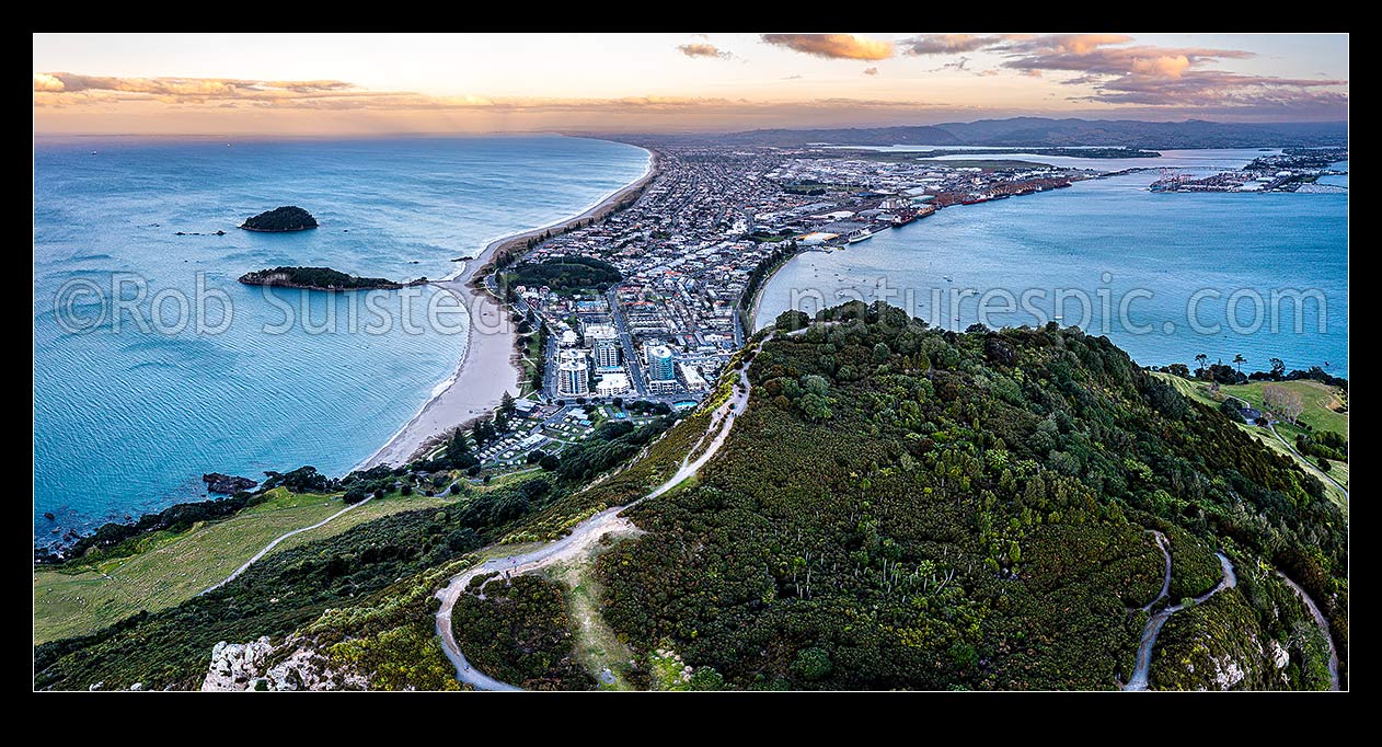 Image of Mt Maunganui summit Mauao at the Tauranga Harbour Entrance. 231m high lava dome. Mt Maunganui Beach left, Tauranga Harbour right. Aerial view at dusk, Mount Maunganui, Tauranga District, Bay of Plenty Region, New Zealand (NZ) stock photo image