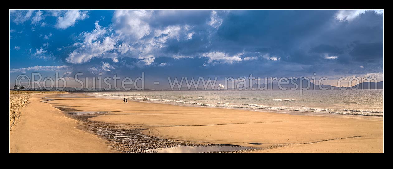 Image of Ruakaka Beach panorama, with people walking in evening light. Mt Manaia (right, 420m) behind right, at the Whangarei Harbour Heads, Ruakaka, Whangarei District, Northland Region, New Zealand (NZ) stock photo image