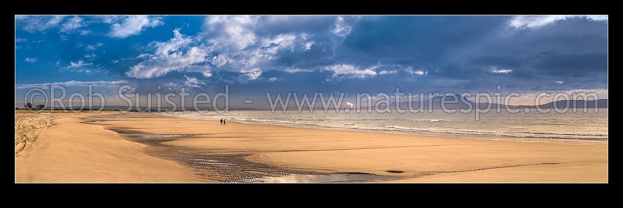 Image of Ruakaka Beach panorama, with people walking in evening light. Mt Manaia (right, 420m) behind right, at the Whangarei Harbour Heads. Wide aspect of 65434, Ruakaka, Whangarei District, Northland Region, New Zealand (NZ) stock photo image